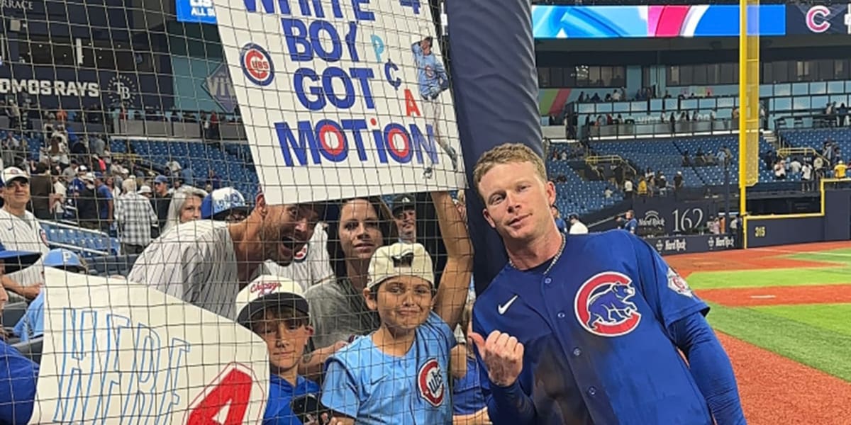 Cubs player Pete Crow-Armstrong posing with emotional young fan holding homemade sign at baseball game