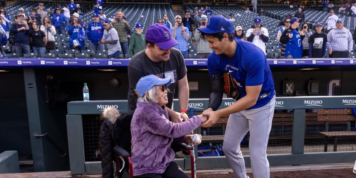 100-year-old woman in wheelchair smiling with Japanese baseball players on field