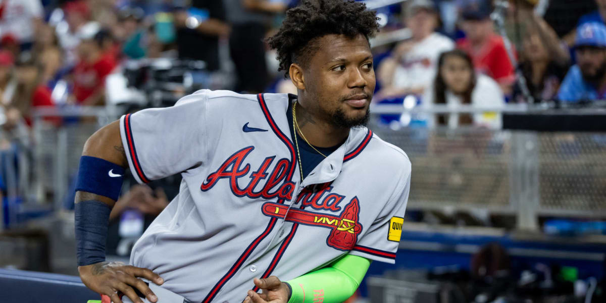 Ronald Acuña Jr. in Atlanta Braves uniform standing ready at dugout entrance with bat