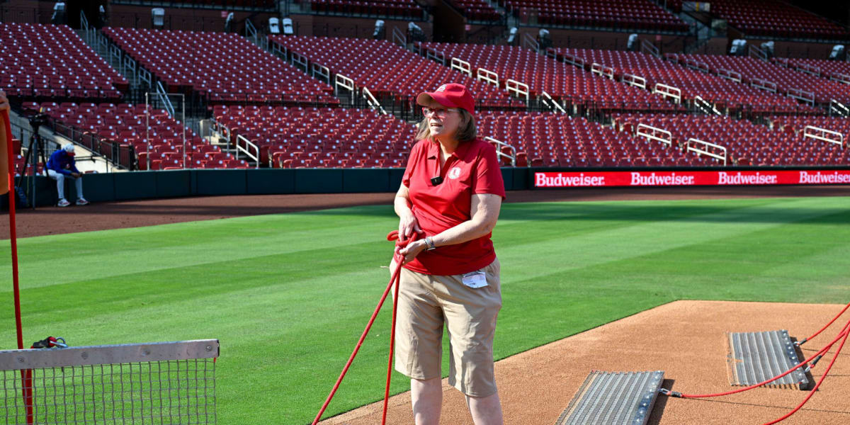 Kimberly Amos wearing Cardinals gear rakes the infield at Busch Stadium