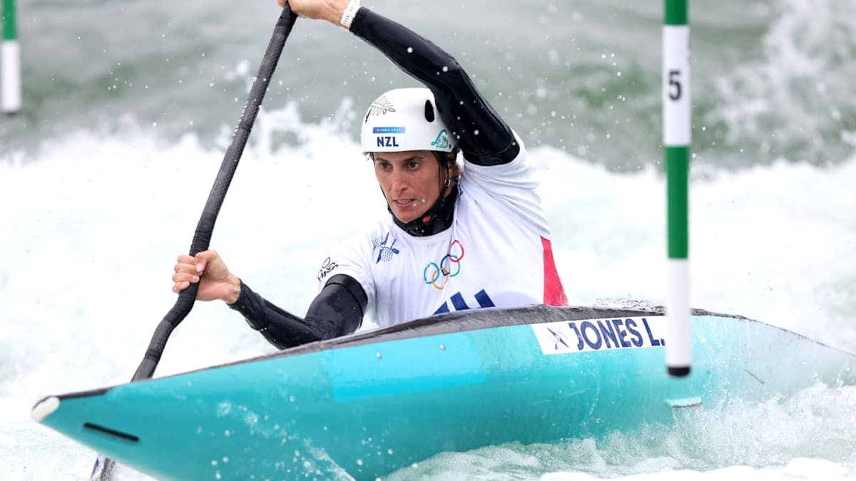 Olympic kayaker Luuka Jones-Yaxley navigating whitewater rapids in competition wearing New Zealand uniform