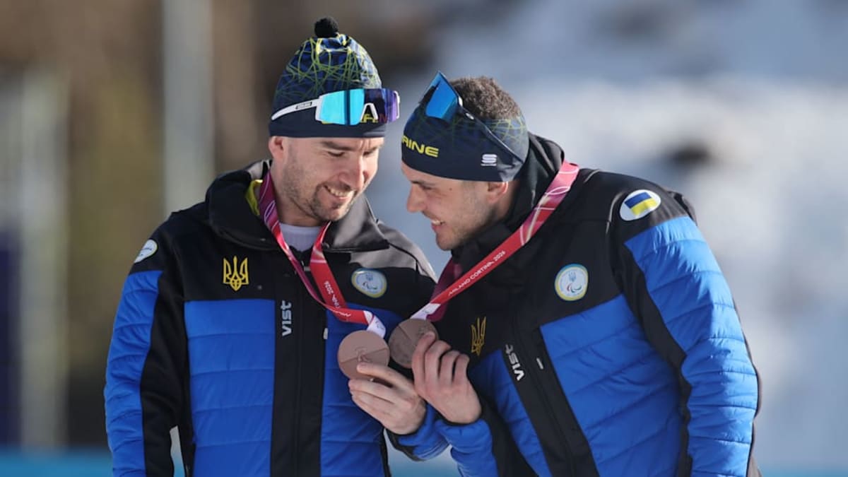 Paralympic athletes competing in biathlon sprint race on snowy cross-country course in Italy