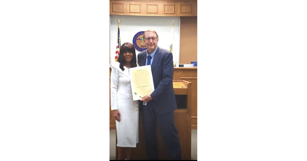 Mayor presenting official proclamation certificate to American High School founder during city council meeting