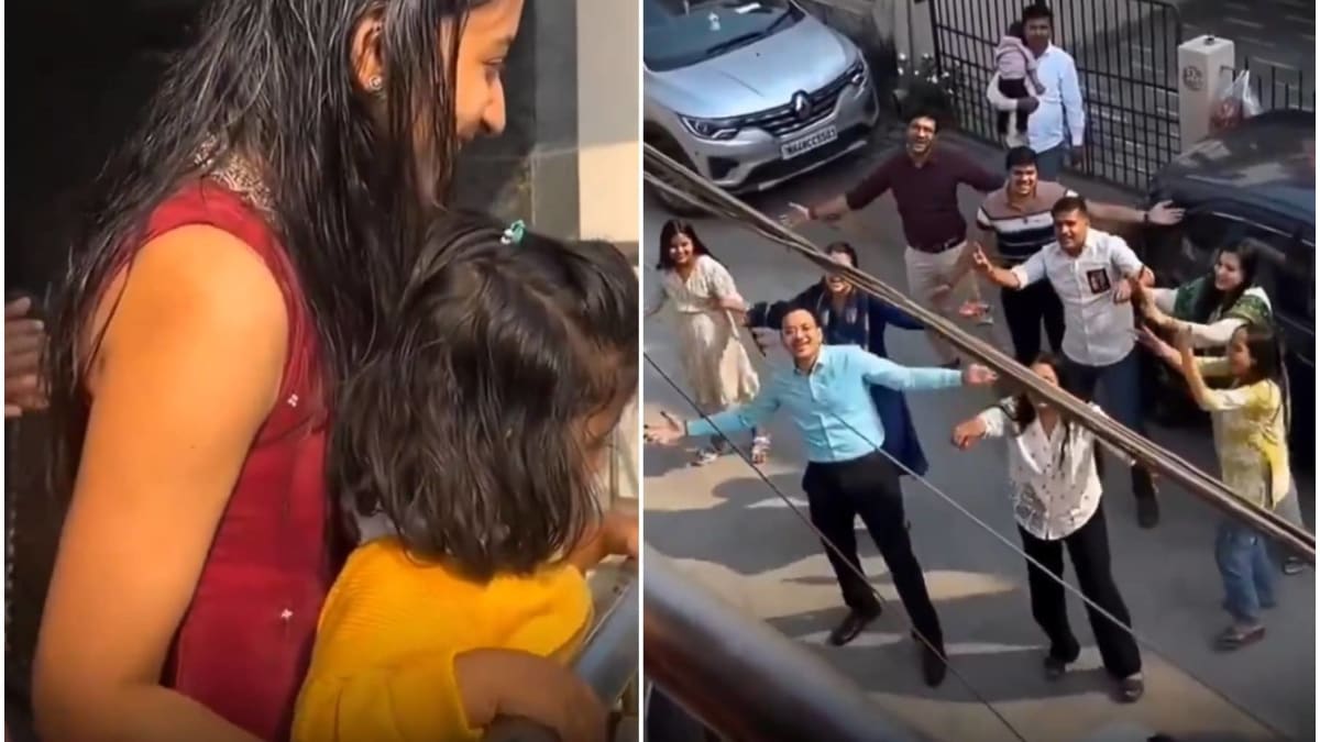 Family dancing energetically in street below balcony during Bollywood-style marriage proposal