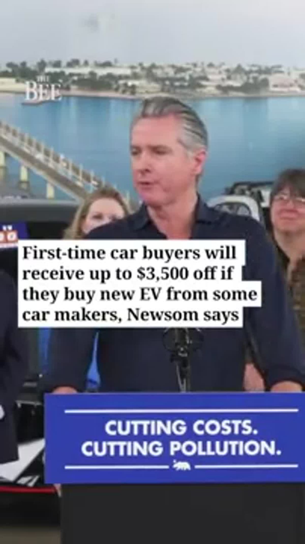 ** Governor Gavin Newsom speaking at podium about electric vehicle rebate program in Oakland