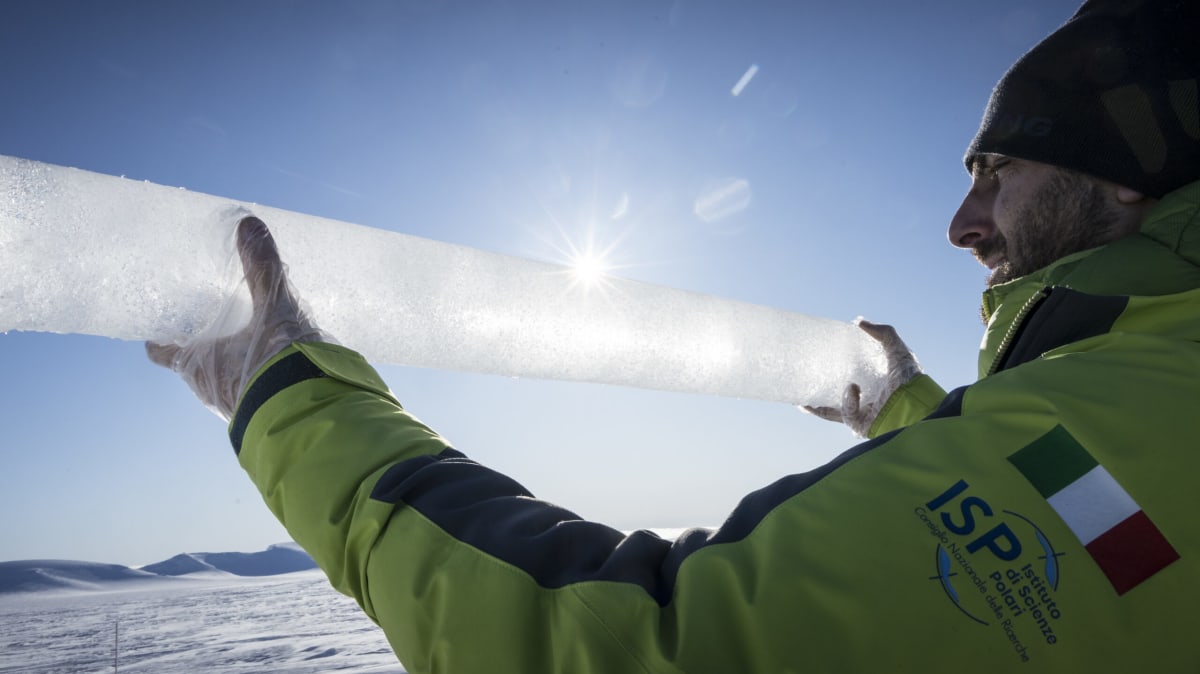 Scientists in winter gear examining cylindrical ice core samples in Antarctic research facility