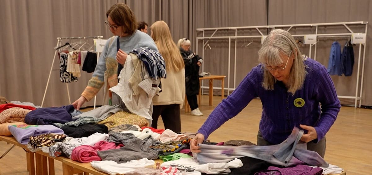 Volunteers sorting and folding secondhand clothes at Stockholm community clothing swap event