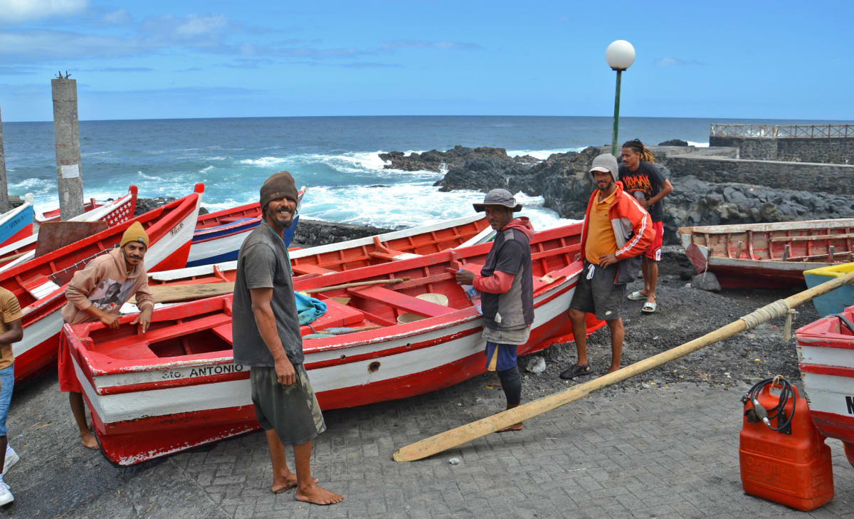 Fisher Alberto Martius and his teenage son Leandro standing with their blue and white fishing boat on Fogo Island shore