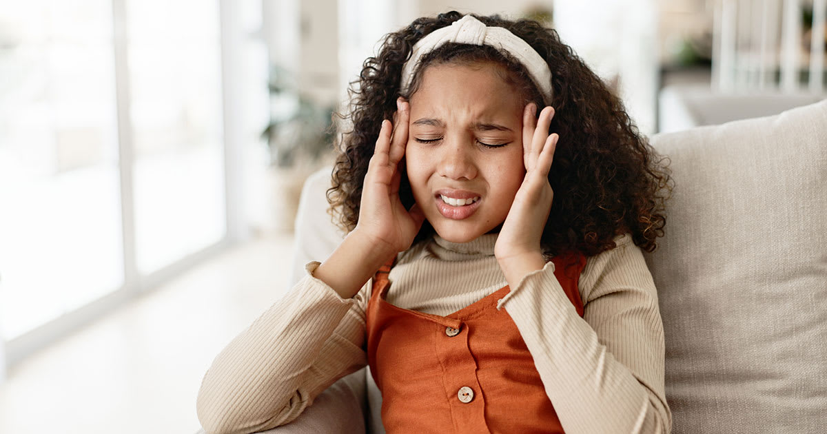 Young teenage girl touching her forehead in pain from a headache