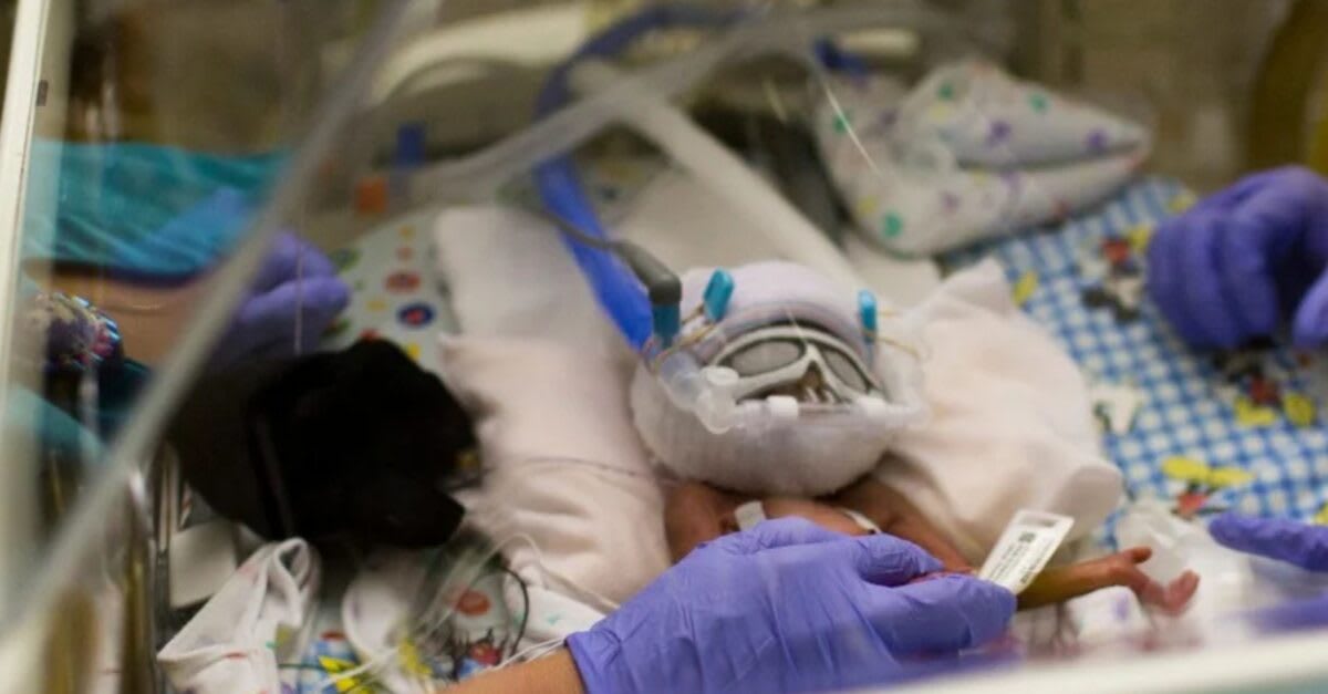 Healthcare worker gently swaddling and comforting newborn baby in hospital NICU setting