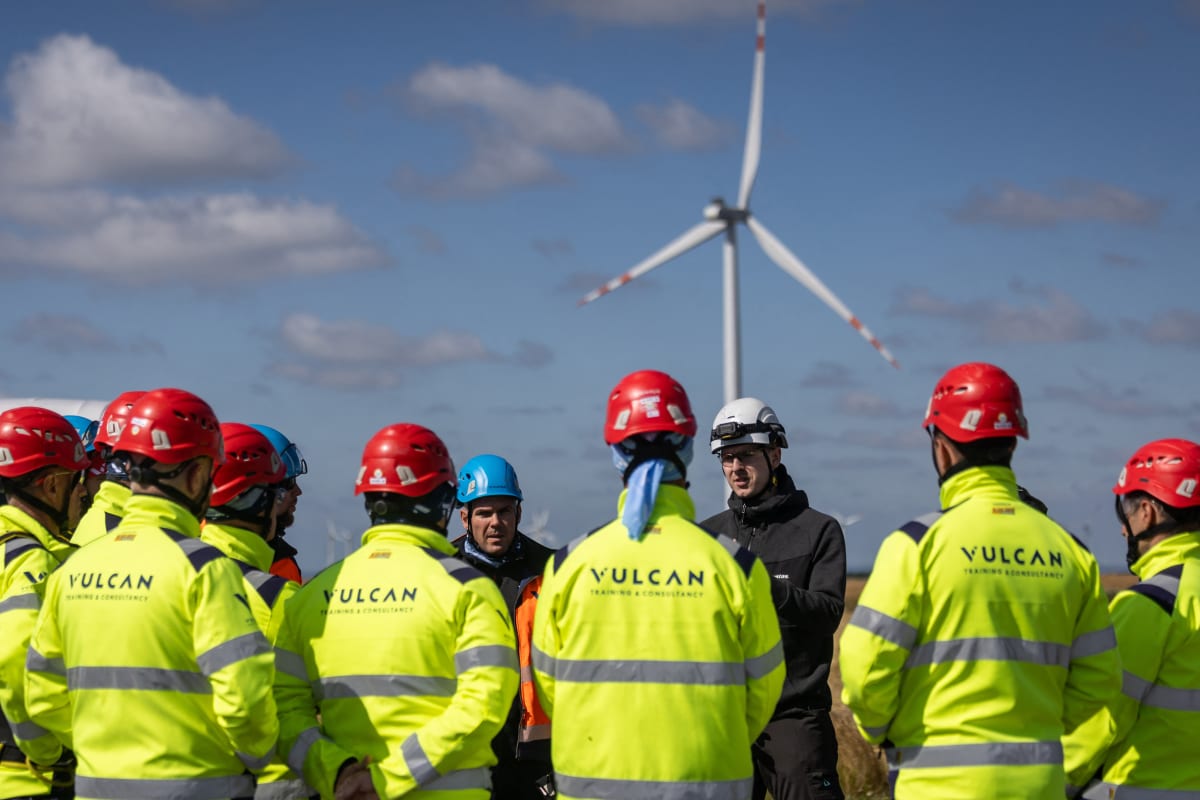 Solar panels and wind turbines in rural landscape with workers installing clean energy infrastructure