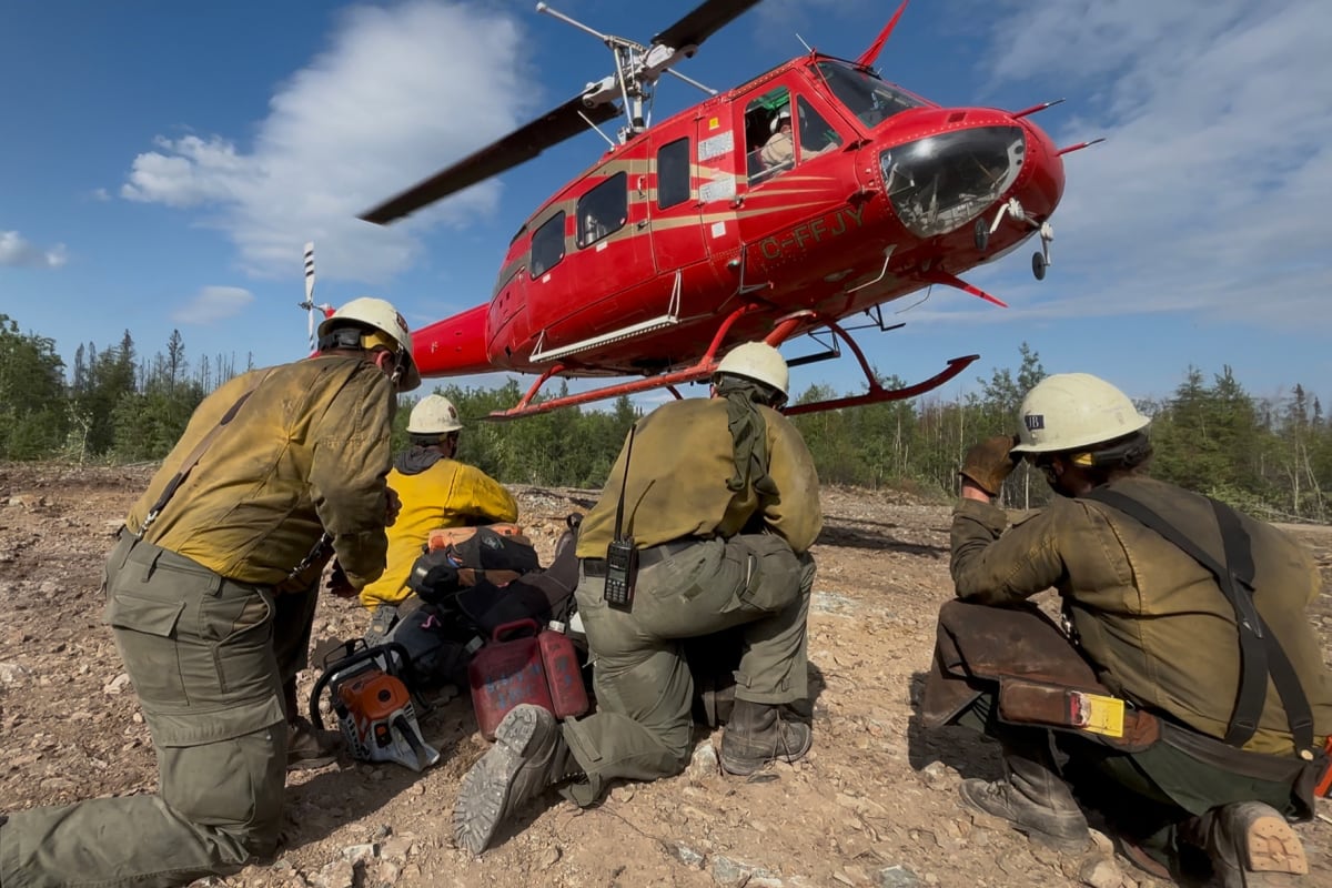 International firefighting crew battling wildfire together with equipment and aircraft overhead