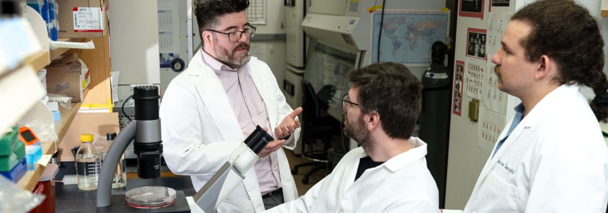 Three cancer researchers Dr. Isaac Harris, Dr. Fabio Hecht, and Dr. Marco Zocchi standing together in laboratory