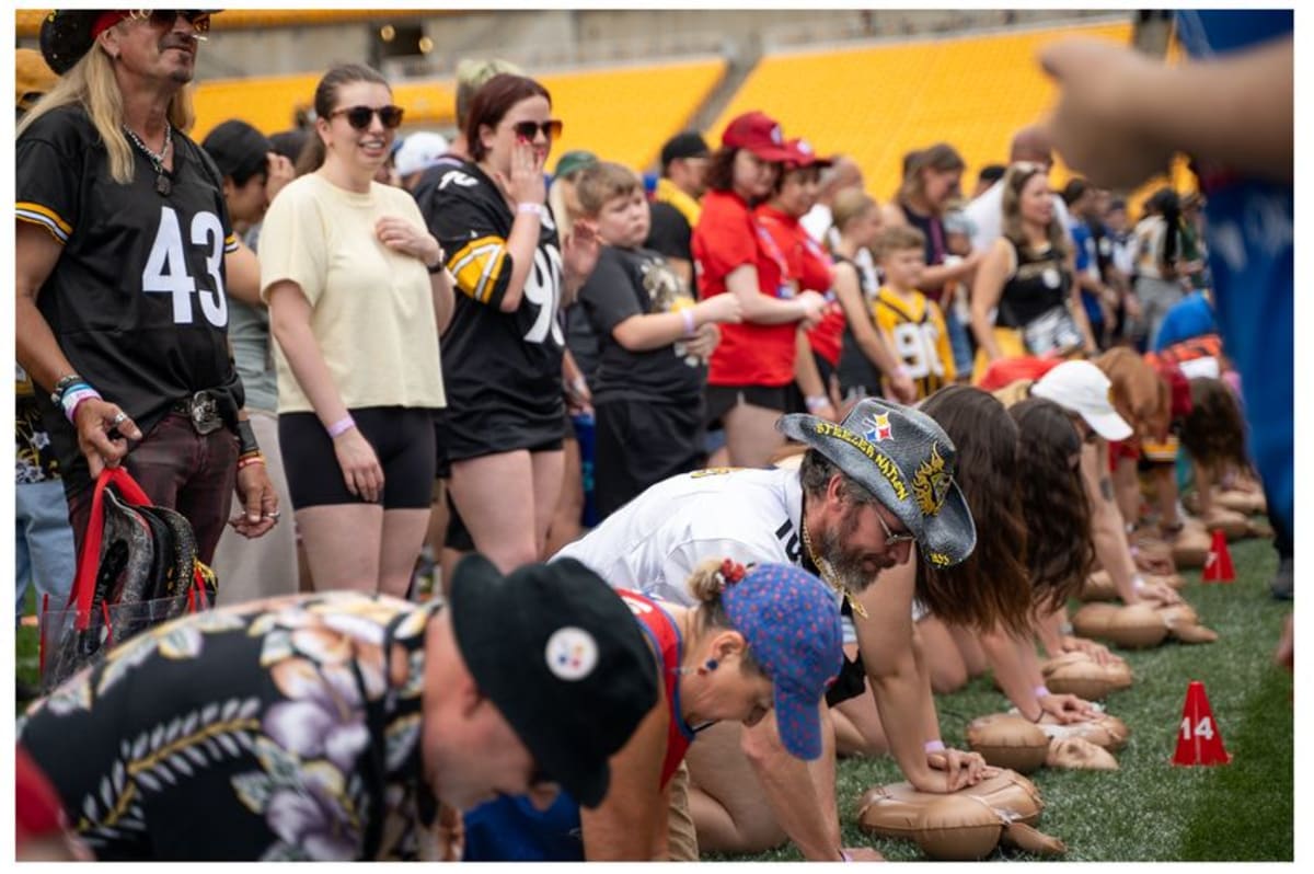 Large crowd learning CPR chest compressions at NFL Draft in Pittsburgh stadium setting