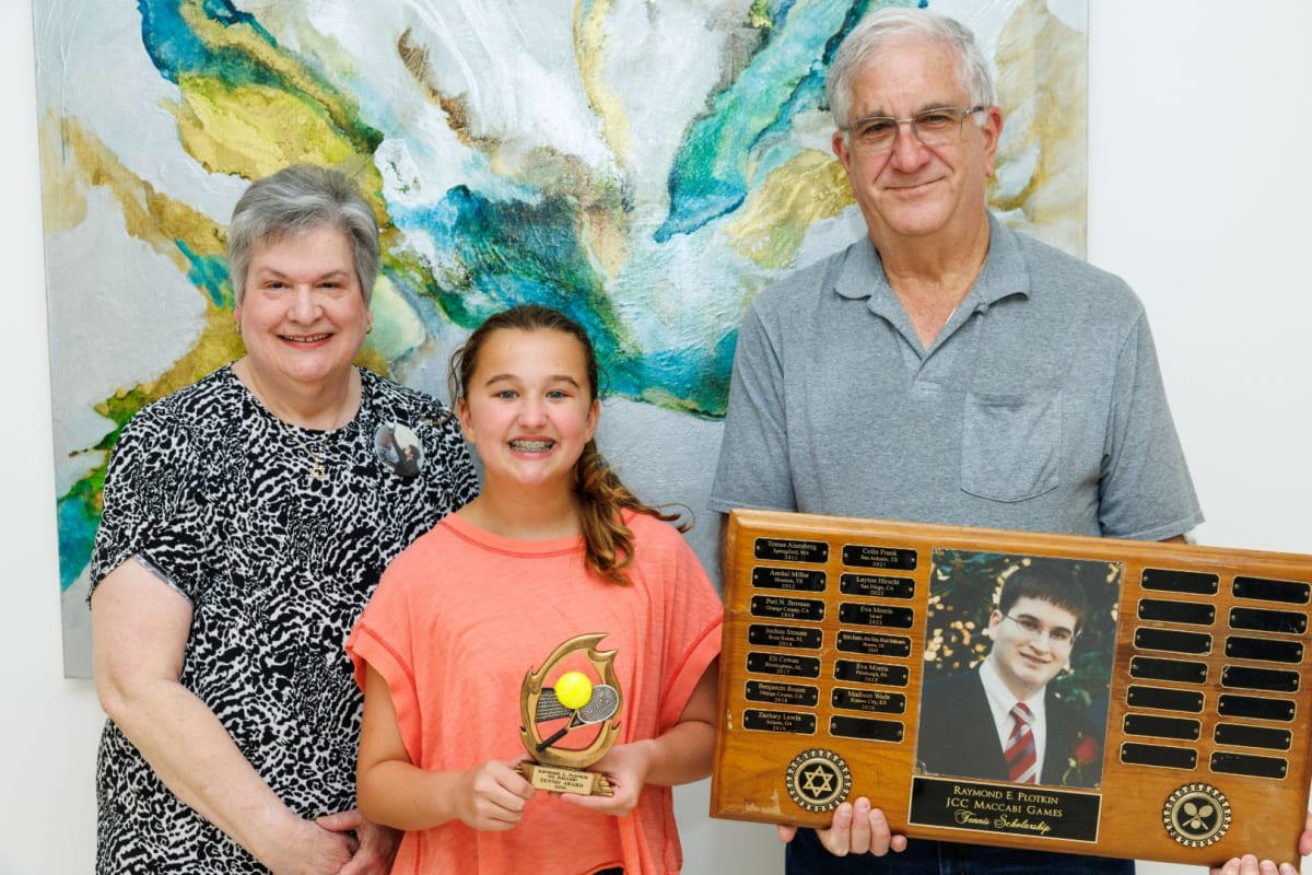 Elaine and Ronald Plotkin stand with scholarship recipient Madison Wade at tennis center ceremony