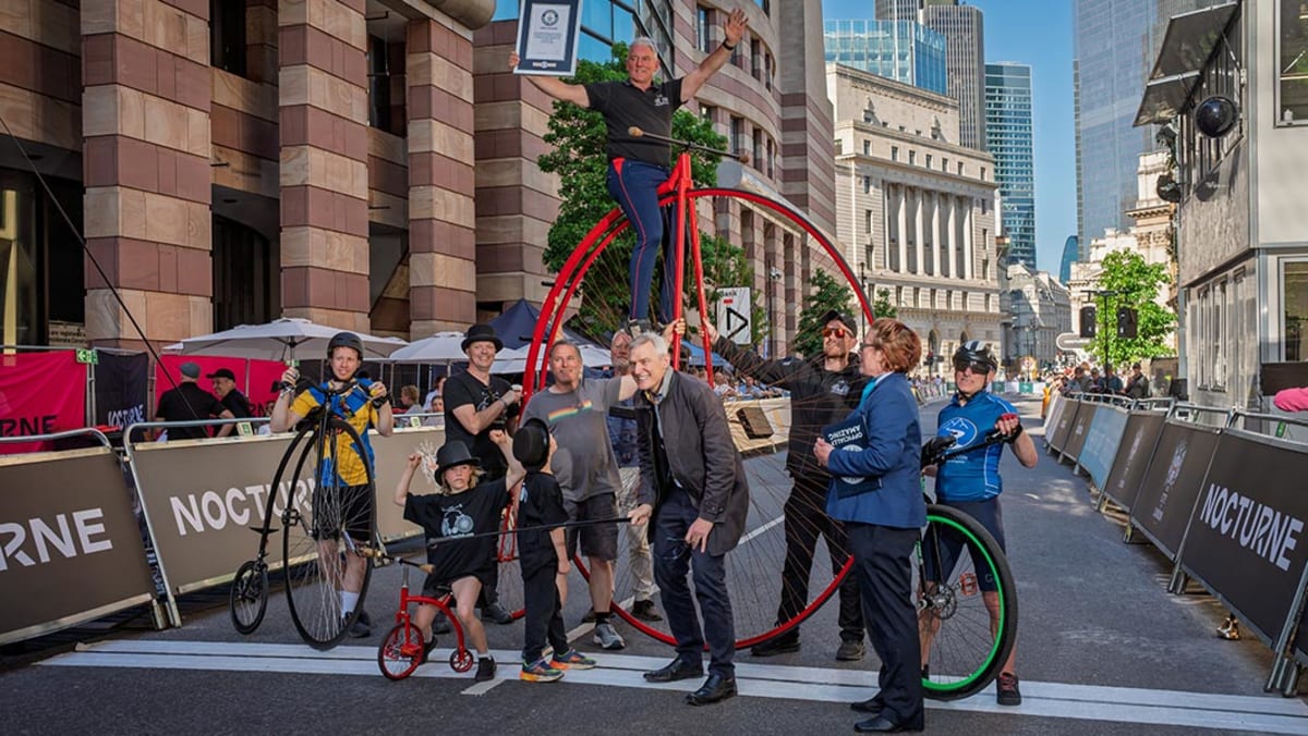 Two young children riding a miniature penny-farthing bicycle at London cycling event