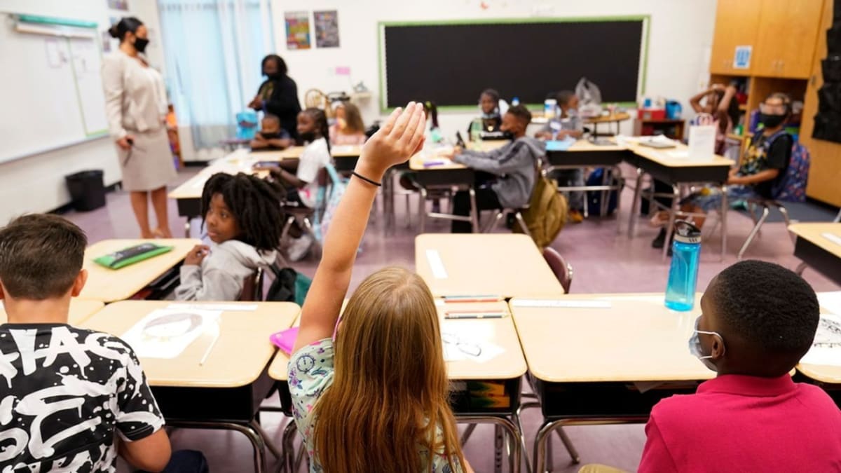 ** Elementary school students raising hands enthusiastically in classroom celebrating academic achievement