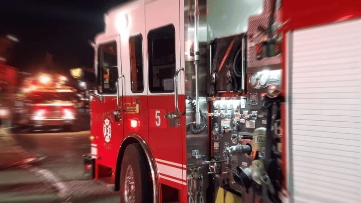 Fire truck at nighttime vehicle rescue scene where car struck tree on rural road