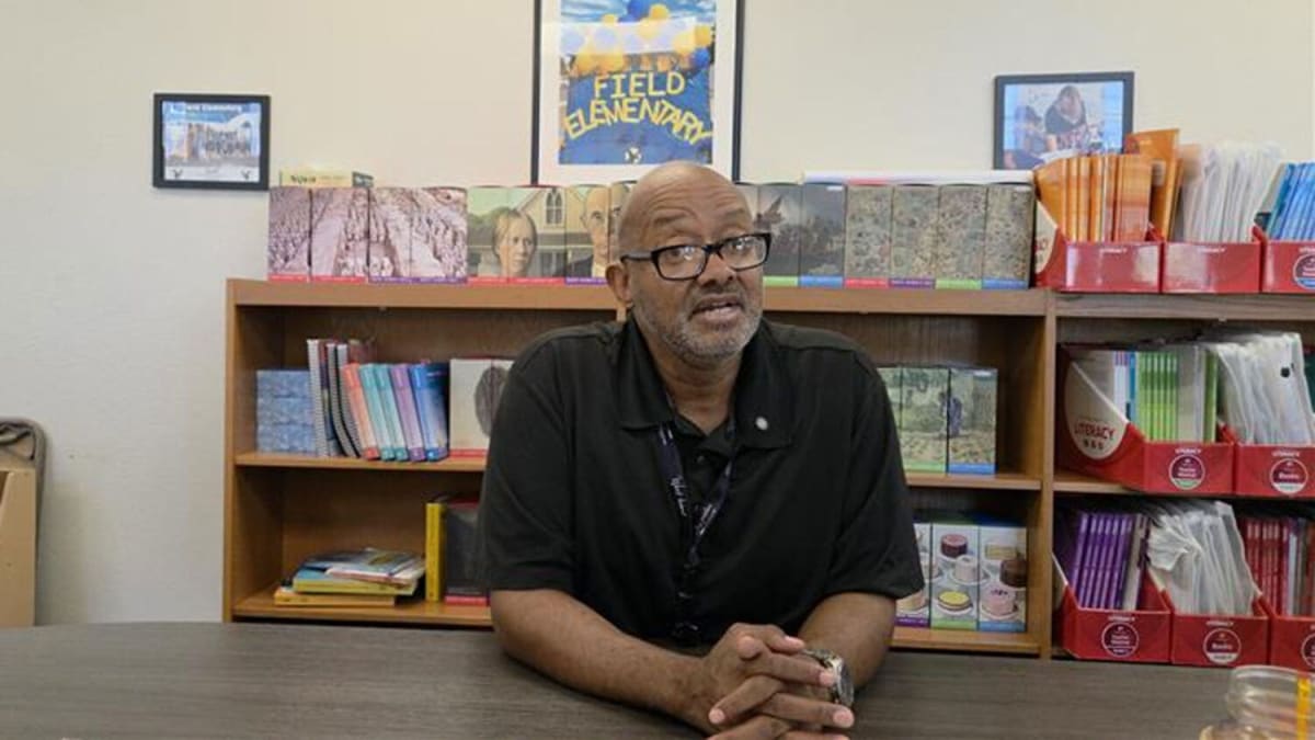 Fourth-grade teacher Jean-Pierre Thompson smiling in his Mesa elementary school classroom