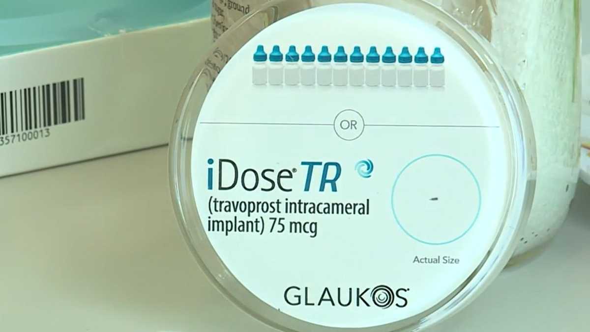 Tiny glaucoma medication implant shown next to human fingertip for size comparison