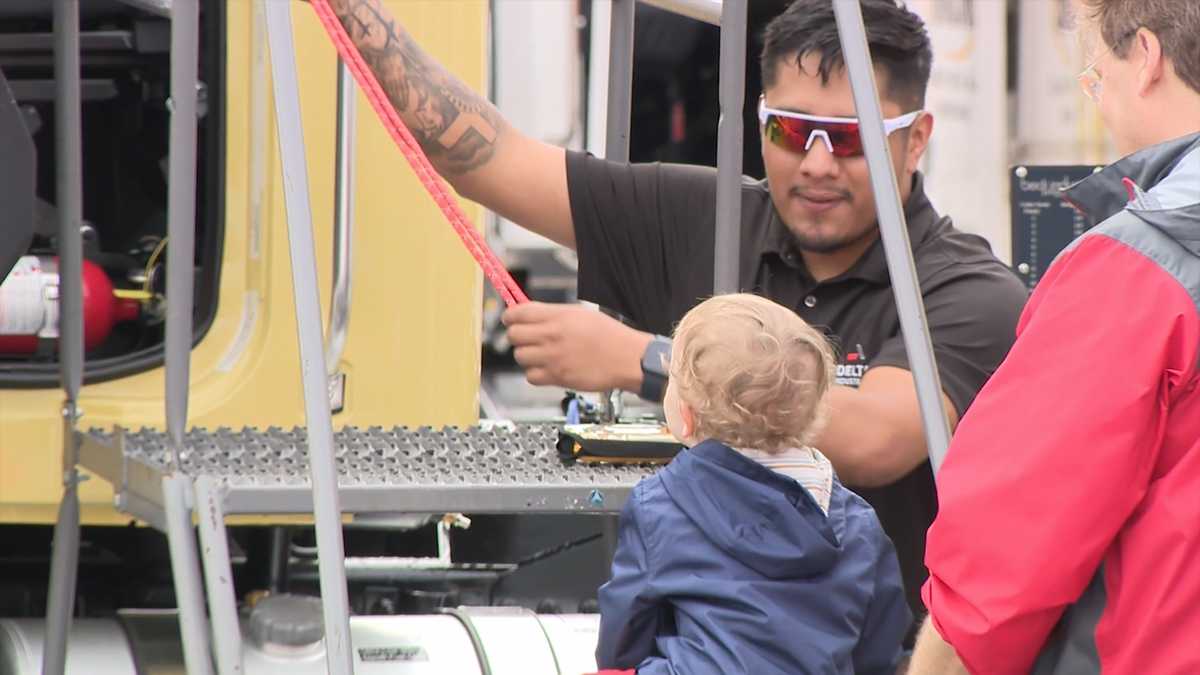 Children climbing and exploring large trucks and emergency vehicles at outdoor community event