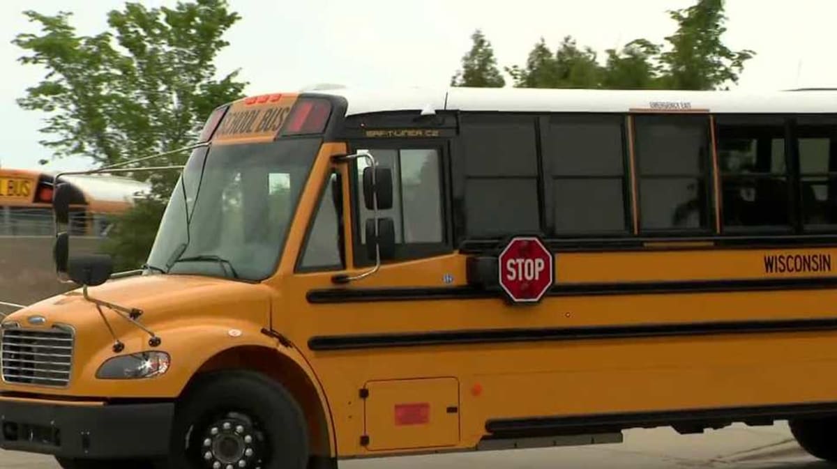 Bright yellow electric school bus with Milwaukee Public Schools branding parked at charging station