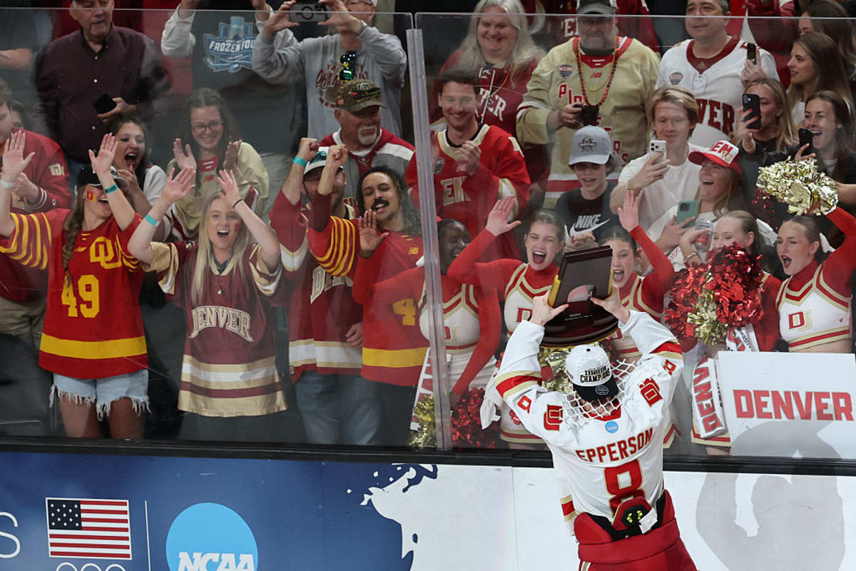 Denver University hockey players celebrating NCAA championship victory on ice with trophy