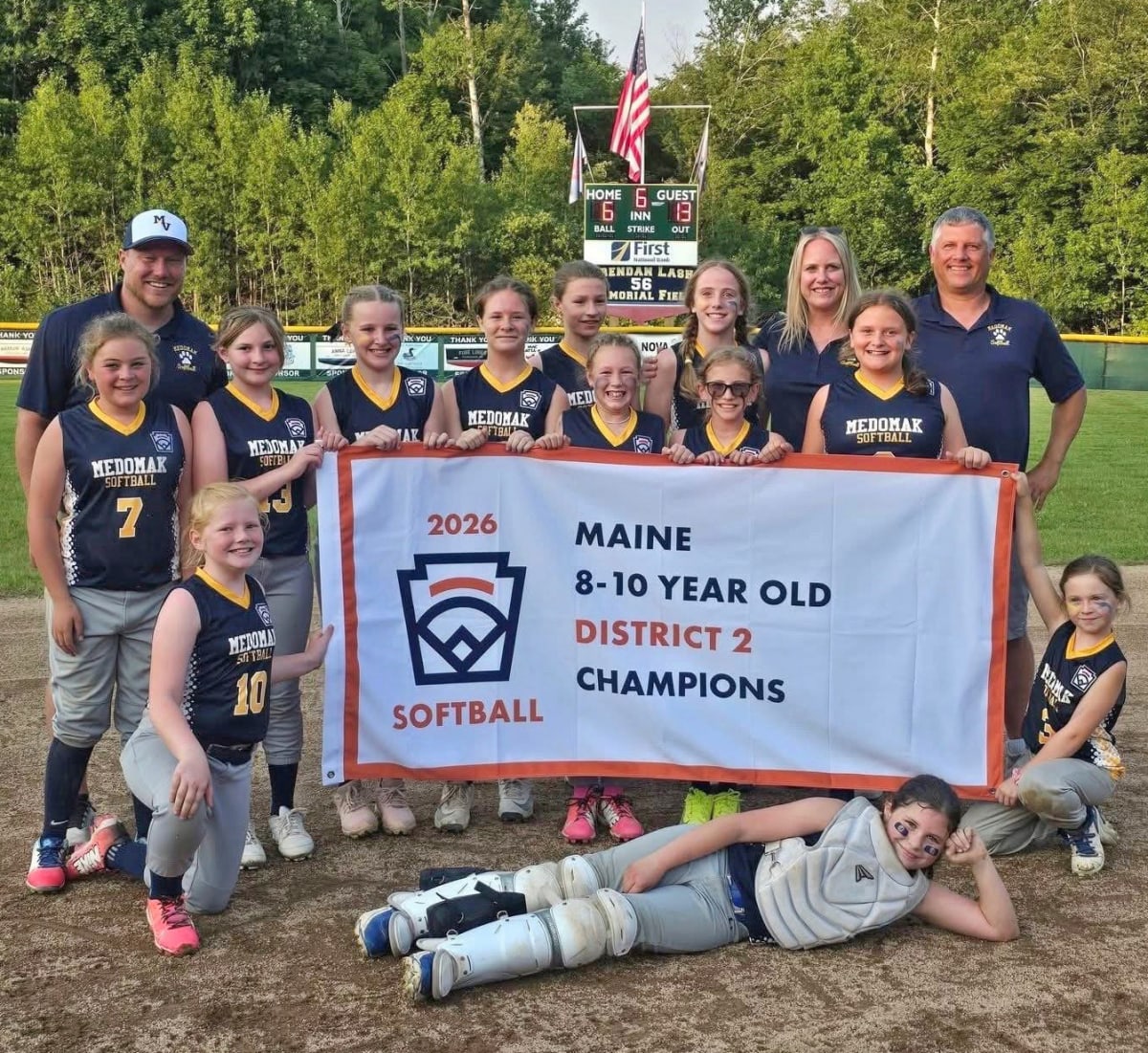 Youth softball team poses with coaches after winning District 2 championship in Maine