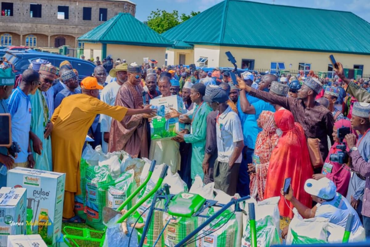 Nigerian farmers receiving modern agricultural equipment including tricycles and tilling machines at community distribution event