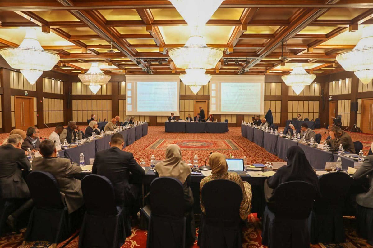 ** Diverse group of community members gathered around table in Tripoli discussing reconciliation and peace building initiatives