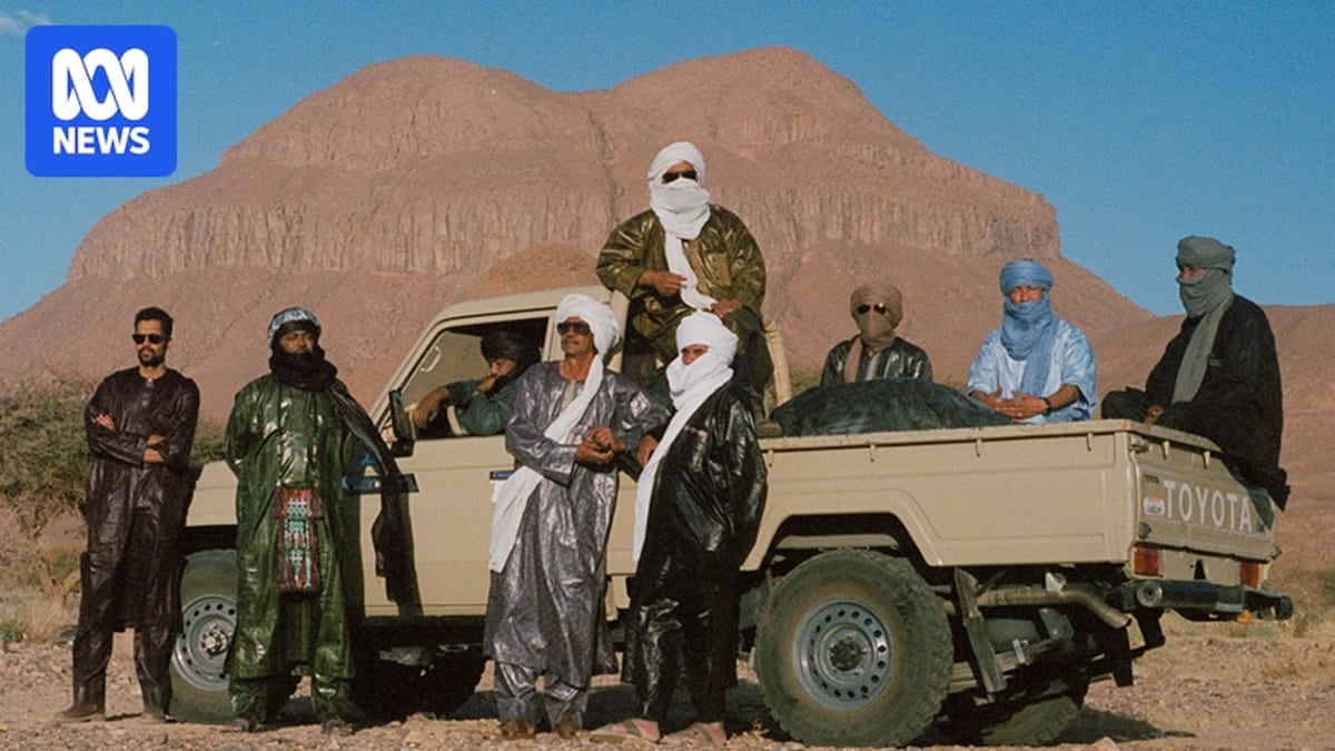 ** Tuareg musicians from band Tinariwen performing with traditional guitars in desert setting