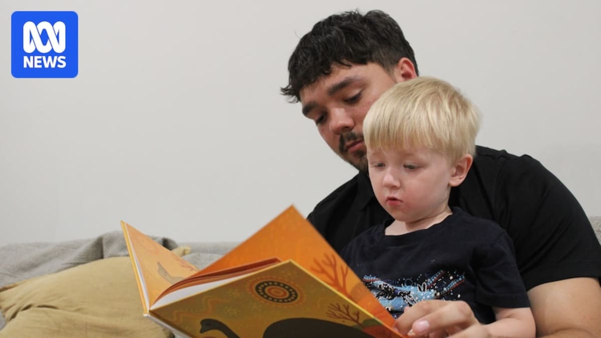 Young Indigenous father reading colorful bedtime story book to his three-year-old son