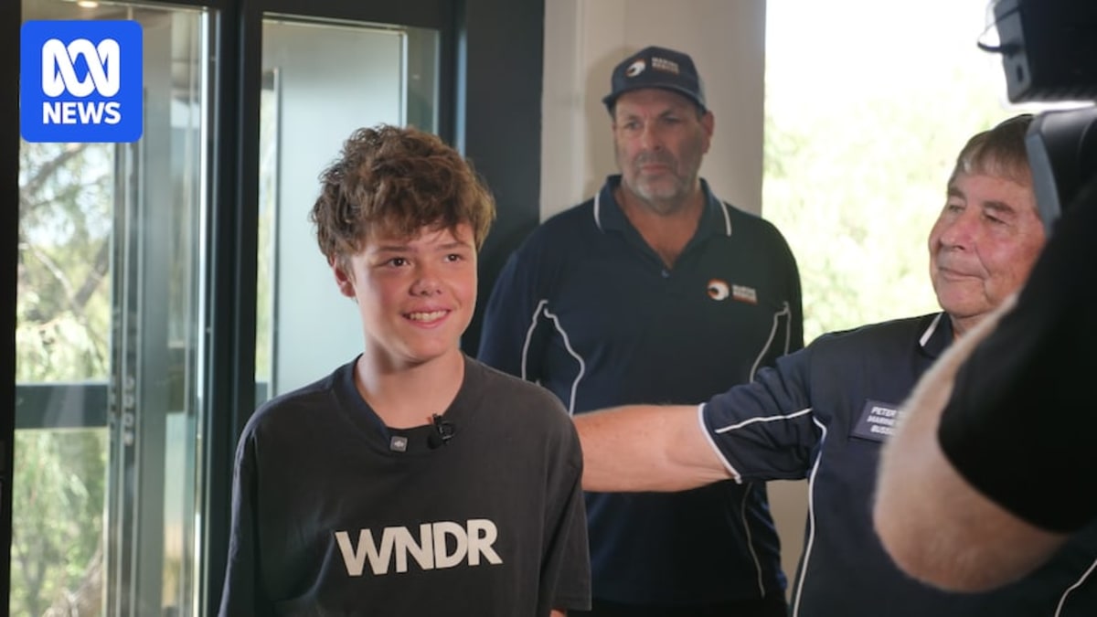 Austin Appelbee standing with his family and marine rescue volunteers on a beach