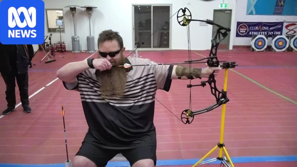 Vision-impaired archer James Griffiths draws bow while wearing blackout glasses at archery range