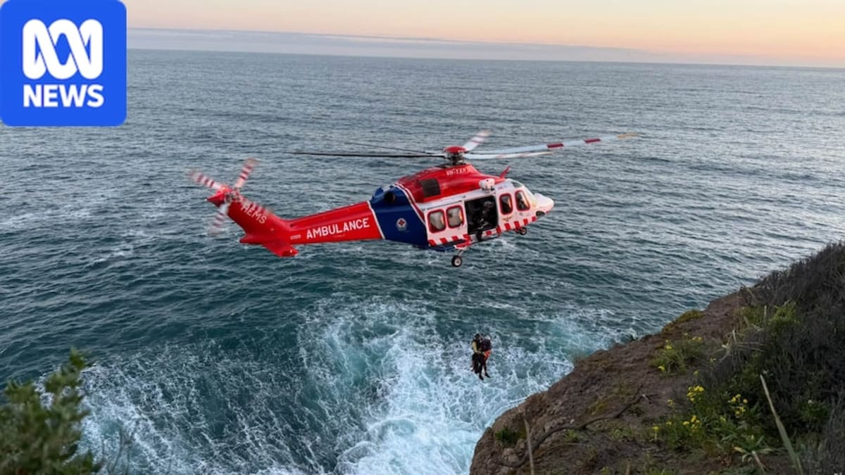 Emergency helicopter winching injured hiker from deep coastal rock crevice during rescue operation