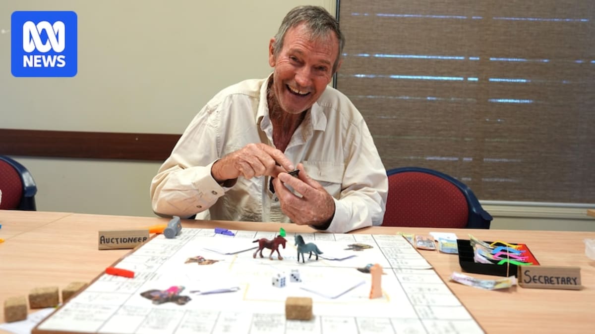 Steve Hawe holding prototype of his Australian campdrafting-themed board game in rural Queensland station