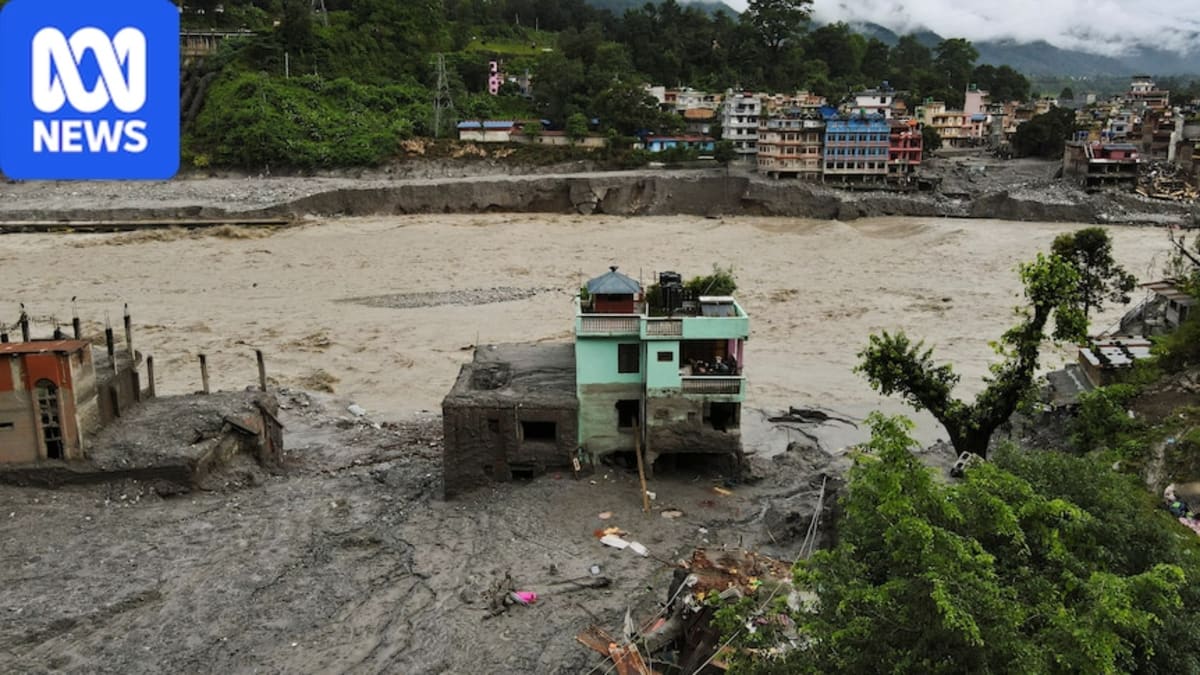 Turquoise two-story house standing alone surrounded by mud and flood debris in Nepal