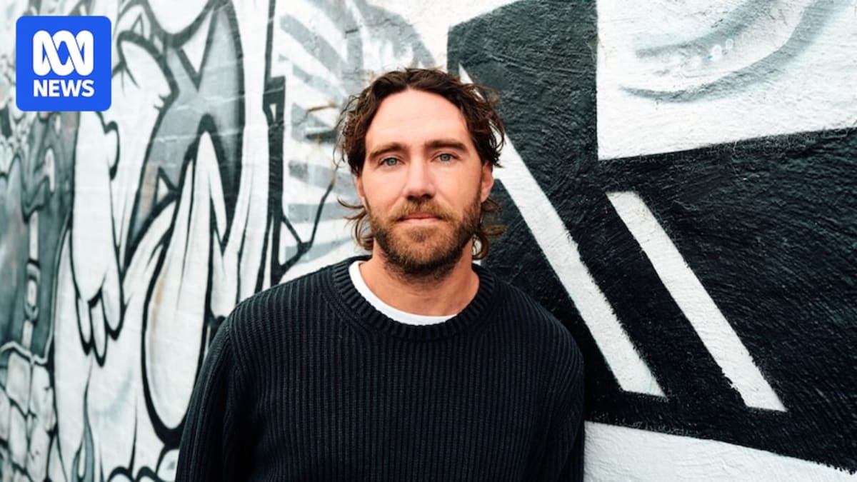 Singer Matt Corby holding guitar, smiling confidently after overcoming performance anxiety