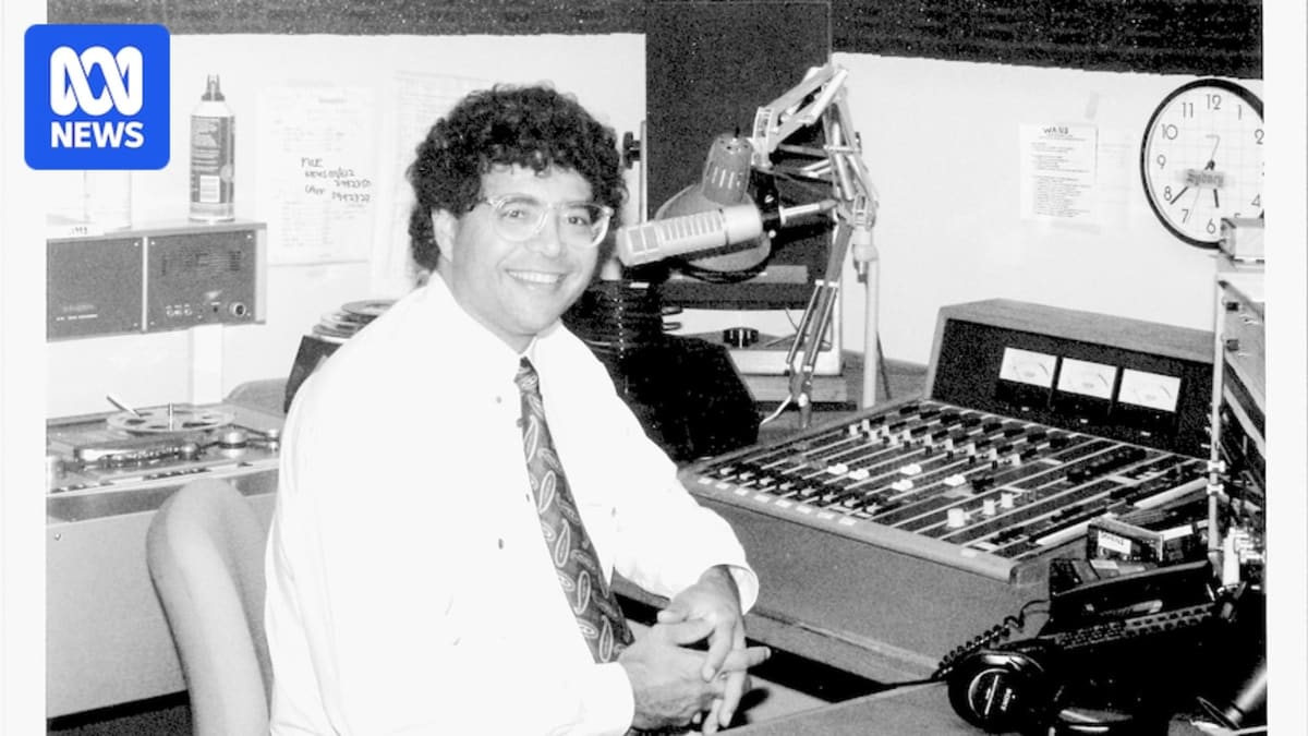 Black and white photograph of Wayne Coolwell smiling at radio broadcasting console