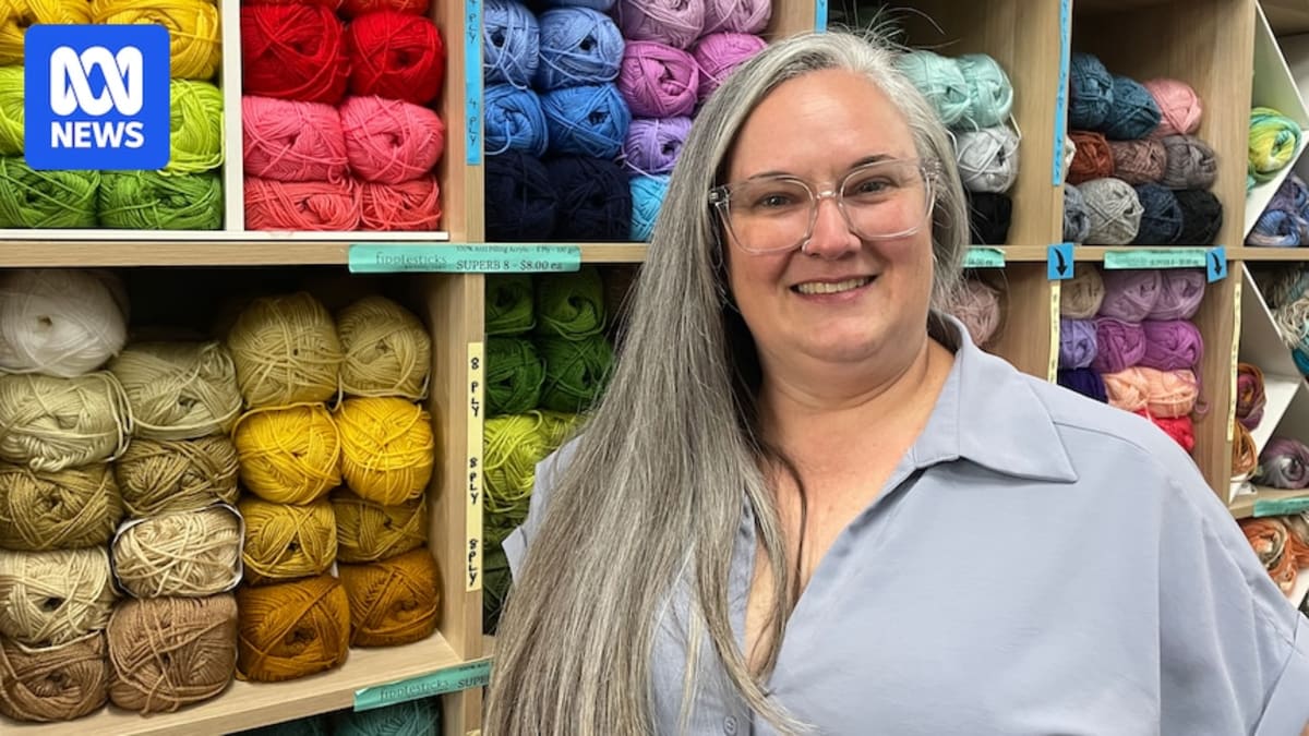 Woman holding colorful knitted blanket made from squares in Australian craft store