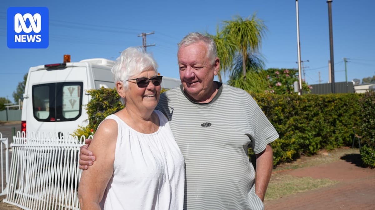 Grey haired couple standing beside their caravan in Mount Isa Queensland outback