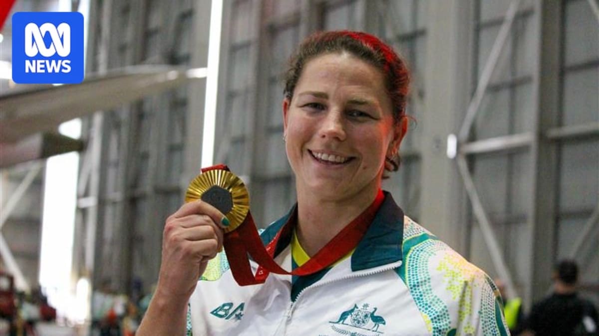 Paralympic rower Nikki Ayers smiling while holding her gold medal from Paris 2024