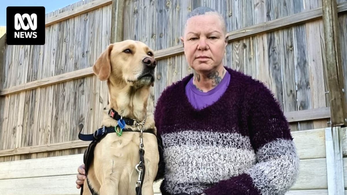 ** Janice Whittle standing beside her retired guide dog Keegan, a yellow Labrador retriever