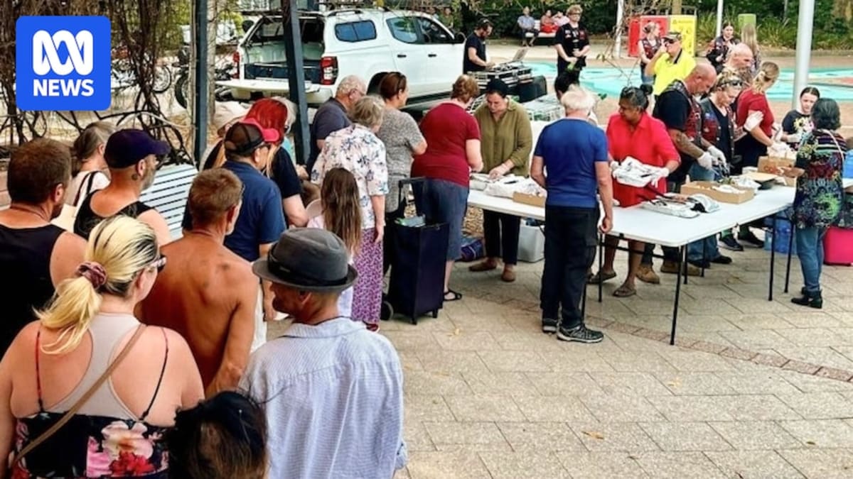 Volunteers serving hot meals from silver trays to diverse community members in Gosford park