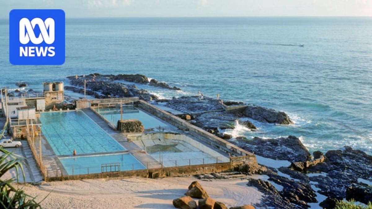 ** Historic black and white photograph of Snapper Rocks ocean pool filled with swimmers in the 1970s