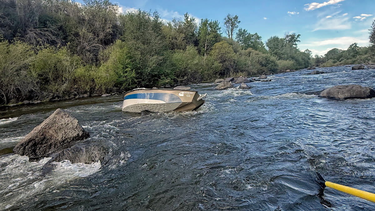 Search and rescue team navigating cataraft through rocky canyon river during rescue operation