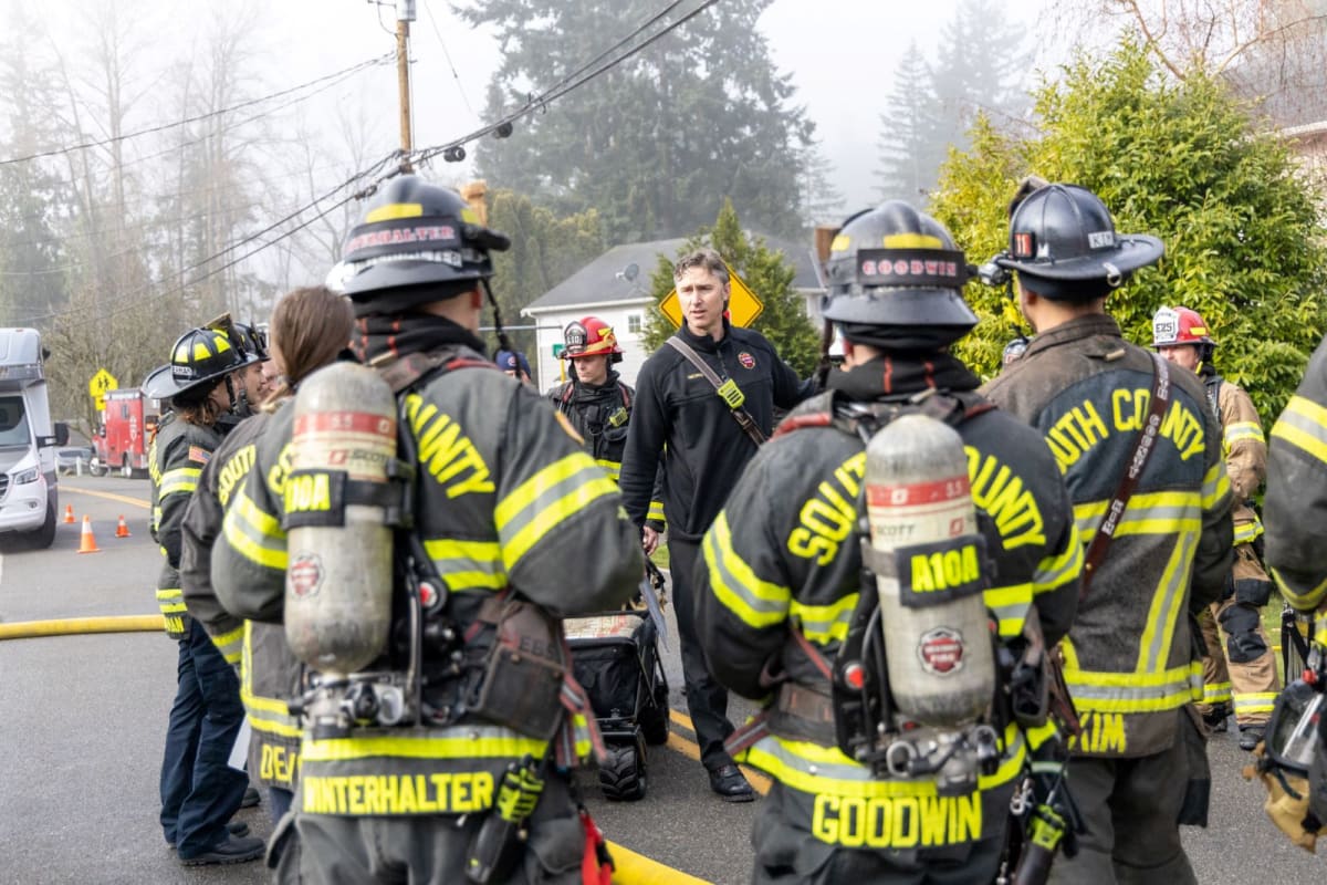 Firefighters responding to house fire with smoke visible from residential structure