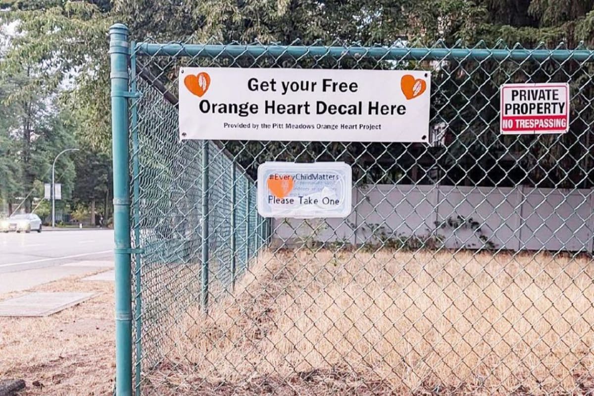 Orange heart stickers in box attached to fence corner for community members to take freely