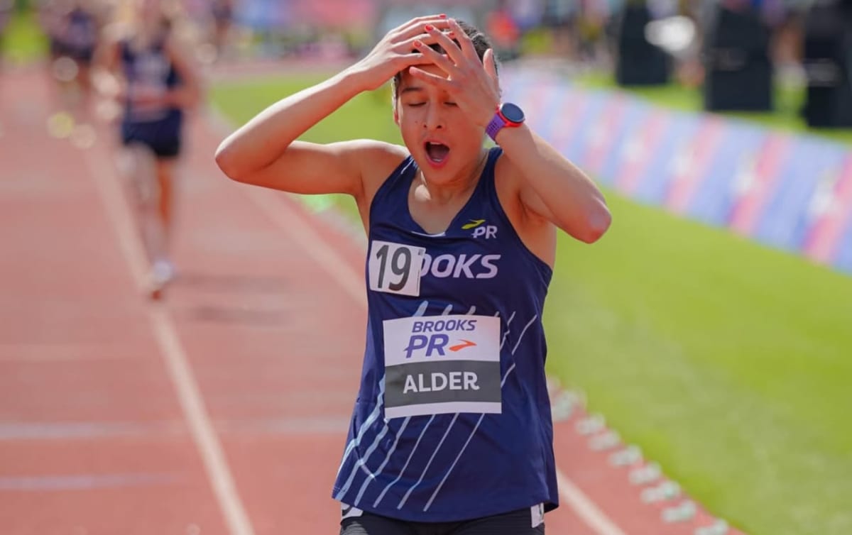 Teenage girl crossing finish line at track meet with arms raised in celebration