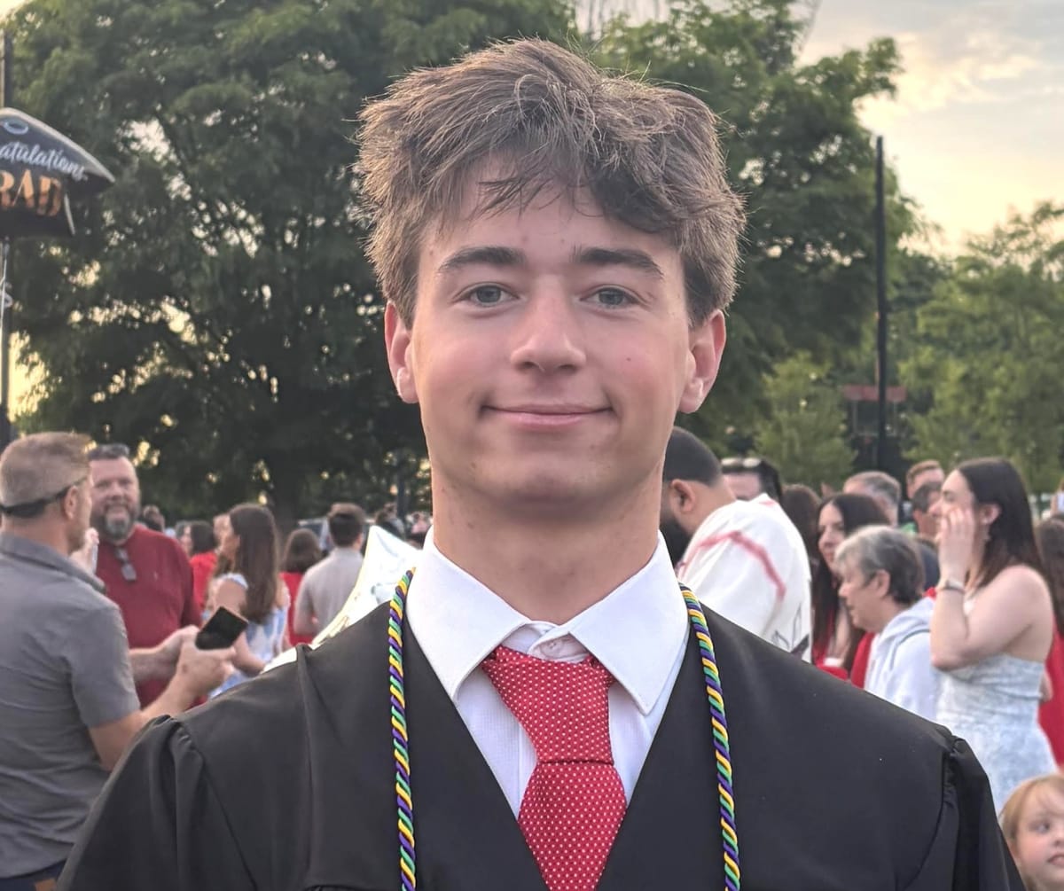 Two smiling Marblehead High School graduates in caps and gowns holding scholarship award certificates
